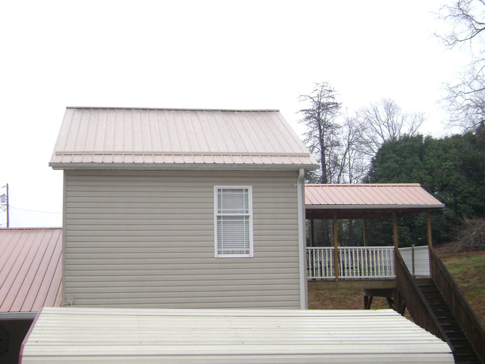 Tan metal roofs on a two story addition and attached porch, from a Roof Replacement job in Hayden