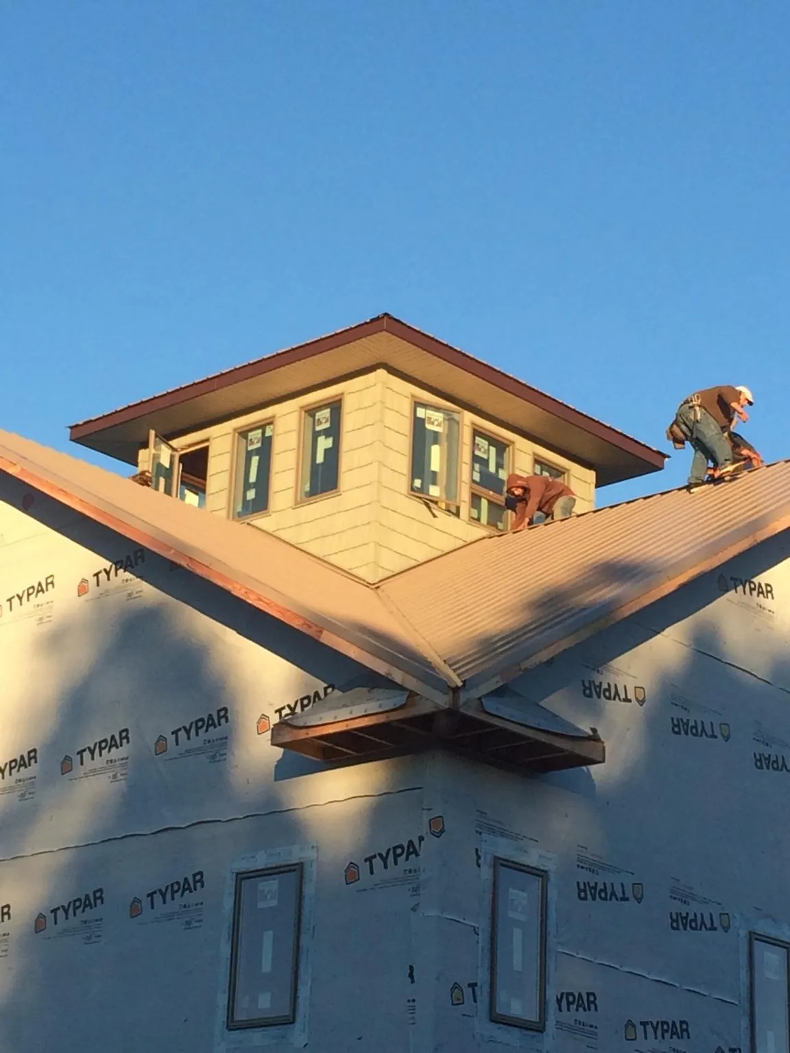 Roofers working around a rooftop cupola on a new metal roof at sunset — Roof Waterproofing in Hayden by Roofing Brothers